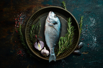 Raw dorado fish with spices and herbs. Preparation. On a dark kitchen background. Top view.