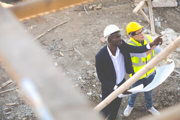 Wall Mural - Top view. Professional Construction and  Engineer team Working on workplace. Professional black architect and construction worker working look at blueprint plan on site.