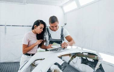 Young woman with man works together in automobile repair garage