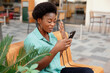 © Sviatlana - Cheerful African woman writes a message on her phone outdoors. The girl communicates with friends and colleagues using a mobile phone. Side view, space for text