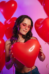 Valentine's Day. Young attractive woman holding a heart-shaped balloon in her hands. Portrait with closed eyes.