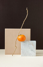 Simple Geometric Minimalism Still Life With Mandarin On Marble With Natural Zig-zag Branch Balance On Beige Table On Brown Background, Vertival, Copy Space