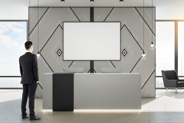 Poster - Businessman standing in office lobby with  blank banner on wall.