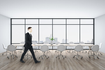 Wall Mural - Businessman walking in conference room with meeting table and city view.