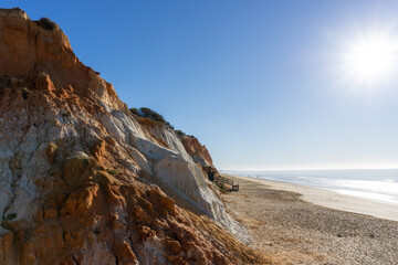 Sticker - view of a wide empty golden sand beach with colorful sand cliffs on a sunny day