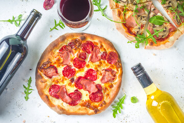 Wall Mural - Pizza party concept.  Set of pizzas with various fillings, Pieces of different pizza, glass and bottle with wine. Flatlay top view copy space on white background