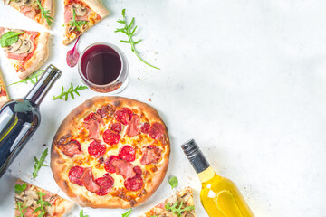 Pizza party concept.  Set of pizzas with various fillings, Pieces of different pizza, glass and bottle with wine. Flatlay top view copy space on white background