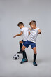 © Roman - active boys play football or soccer isolated over gray background. little champions hold competition