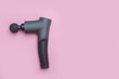 Therapeutic massage gun on pink background with copy space. Sport recovery concept.
