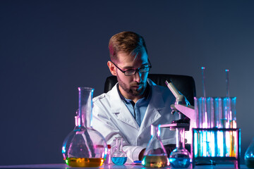 Poster - scientist on the background of test tubes and a microscope. the chemist is sitting in the lab. a che