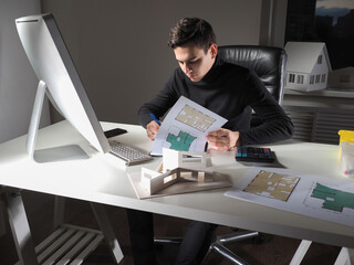 Poster - Construction engineer is working on the project of a new house. The architect makes notes on the drawings of the building. The man works in an architectural firm. The workplace of the architect.
