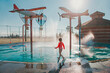 © anoushkatoronto - Cute adorable Caucasian funny girl playing on splash pad playground on summer day. Seasonal water sport recreational activity for kids outdoors.