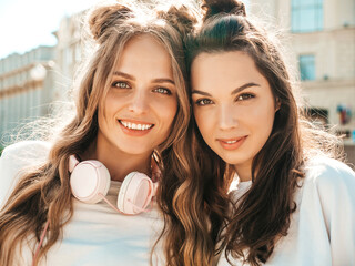 Portrait of two young beautiful smiling hipster female in trendy summer white t-shirt clothes.Sexy carefree women posing on street background. Positive models having fun and hugging