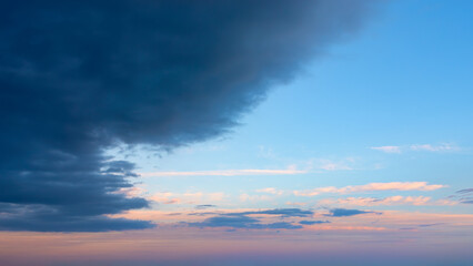 Wall Mural - large dark storm cloud obscures the clear pink blue vanilla sky at dawn. calm before the storm, sere