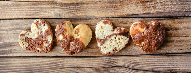 A row of heart-shaped buns on a wooden background. Flat layout banner