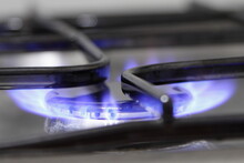 Stainless steel gas stove hob with blue fire close up, kitchen indoor fire safety
