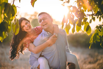 Outdoor portrait of young couple, boyfriend carrying girlfriend on his back.