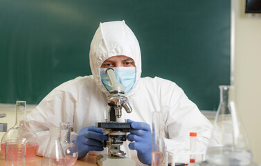 A scientist chemist in the laboratory conducts a study of viruses carefully studied with a microscope.