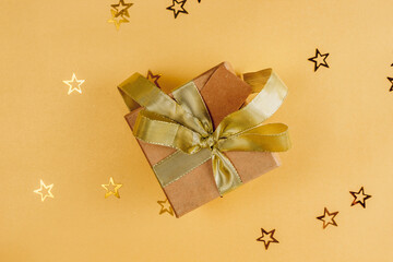 Wall Mural - Flat Lay Christmas or Party Background with craft gift box with gold bow on golden background.