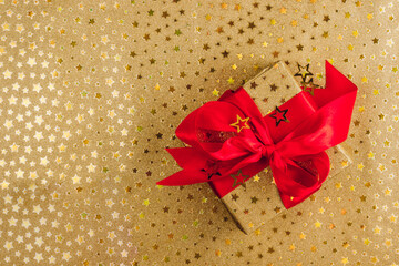 Wall Mural - Flat Lay Christmas or Party Background with gold gift box with red bow on golden background.