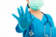 © sorapop - Female nurse with stethoscope puts rubber gloves and wearing medical face mask, woman doctor in blue uniform show hand up stop sign, studio shot isolated over white background, medical health concept