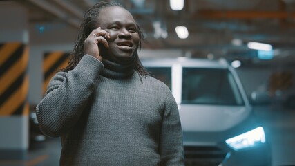 Excited african american black man having phone conversation in the underground parking. High quality photo