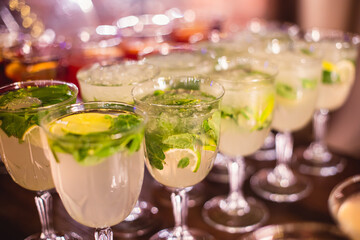 View of alcohol setting on catering banquet table, row line of different colored alcohol cocktails on a party, martini, vodka, spritz and others on decorated catering table event