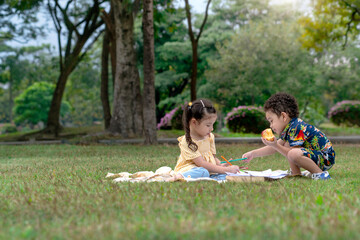 boy and girl playing on lawn, cute little children sitting draw together in nature outdoor at park