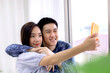 © monster_code - Asian couple making a selfie at hotel room by smartphone. Asian couples taking selfies at resort room. Journey, Travel concept. Honeymoon trip