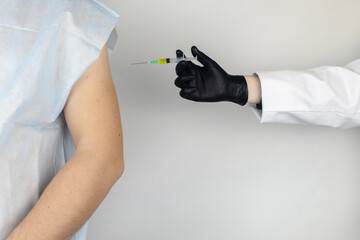 Infectious disease doctor gives the patient a medical vaccination in the shoulder. Immunization against tetanus, influenza, dysentery, whooping cough, diphtheria, measles, shigellosis and hepatitis B