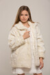 © Alexander - beautiful child girl with long hair in a white dress and short fur coat posing on a white background