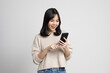 Pretty young asian woman using smartphone standing on isolated w