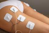 Fototapeta  - Massage the buttocks and legs with a myostimulator with attached electrodes.