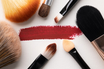 Top view cosmetics makeup for female on the white table background with Different brush types.