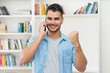© Daniel Ernst - Cheering latin american hipster man talking at mobile phone