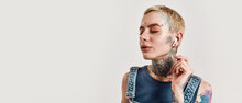 Listening To Music. A Close Up Of A White Girl Tattooed With Piercing Wearing Denim Overall Standing And Listening To Music With Her Wireless Earphones And Eyes Closed
