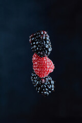 Falling fresh berries drops on the black background