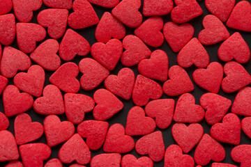 Red Hearts Candy on black surface close up. Valentine's day concept. Macro. Sweet red candy texture