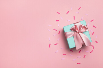 Gift box and confetti on pastel pink background. Birthday party, Valentines day or mother day greeting card. Top view, flat lay, copy space