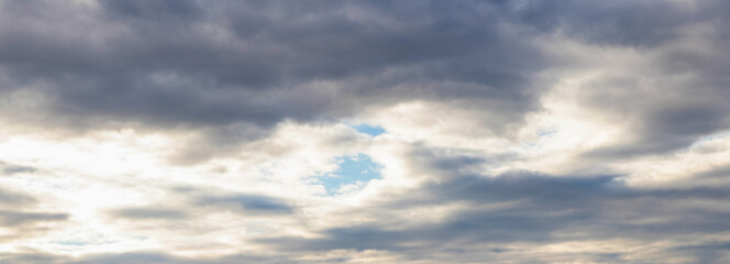 through the dark clouds in the sky you can see a piece of blue sky, panorama