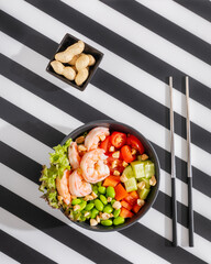 Poster - Poke bowl with shrimps top view on striped black and white background with chopsticks top view