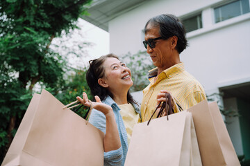 Senior husband and wife carrying shopping paper bags.