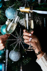 women's hands holding champagne glasses on the background of a C