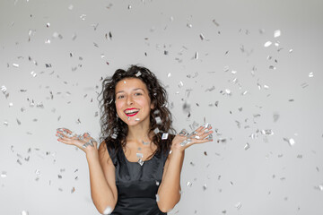 the emotion of success. happy sexy brunette girl is enjoying celebrating with confetti on a white ba