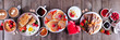 Valentines or Mothers Day brunch table scene. Overhead view on a dark wood banner background. Heart shaped pancakes, eggs and a variety of love themed food.