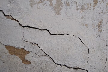 Wall Mural - Grunge texture of an old concrete wall with peeling plaster and cracks. City view, old cracked wall.