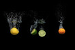 Fresh citrus fruit falling into the water isolated on a black background.