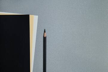 Black, yellow and white sheets of paper and a black pencil on a gray background. Flat lay, copy space, top view