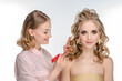 © Miramiska - Stylist makes girl's hair. Combing female hair. Hair care for woman. Stylist makes an evening hairstyle for model at photo shoot.