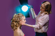 © Miramiska - Stylist makes girl's hair, hair spray. Combing female hair. Hair care for woman. Stylist makes an evening hairstyle for model at photo shoot applies hairspray.
